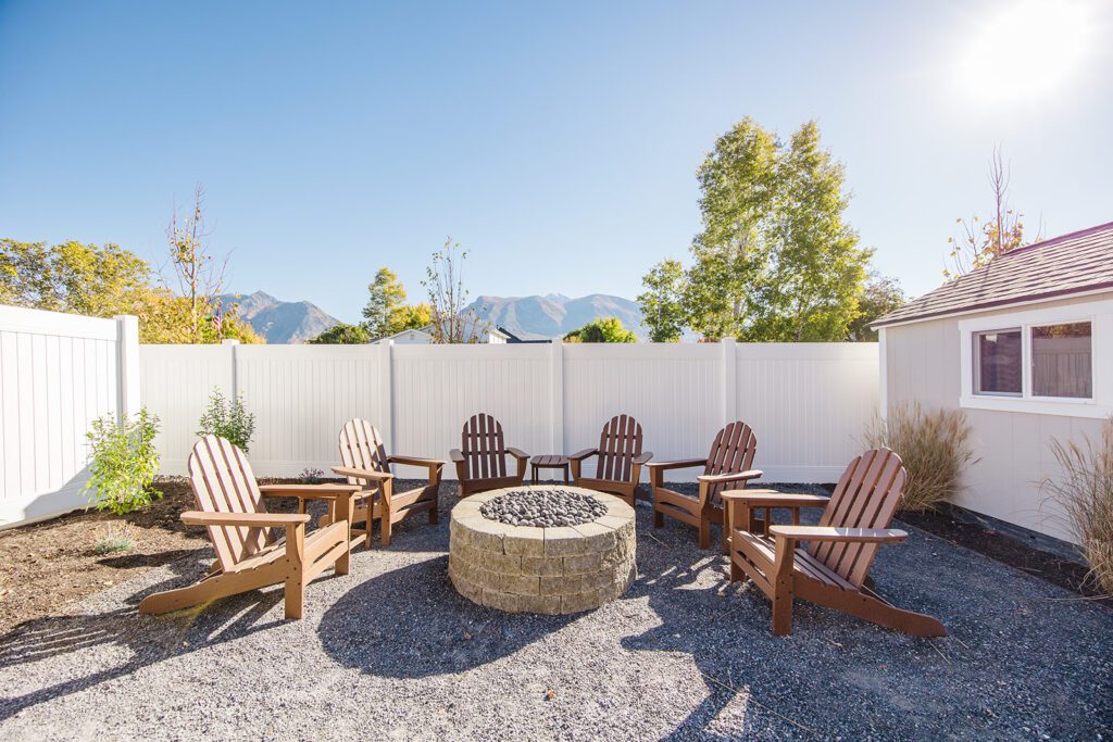 Back exterior of a Utah custom home with large windows, patio space, and beautiful yard design