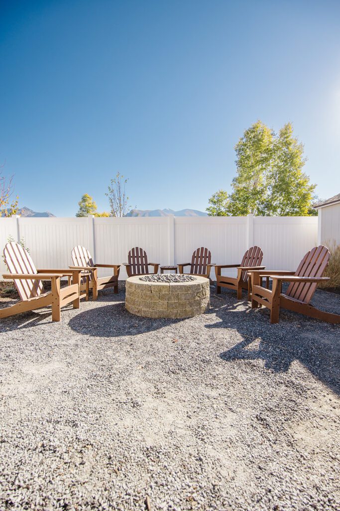 Back exterior of a Utah custom home with large windows, patio space, and beautiful yard design