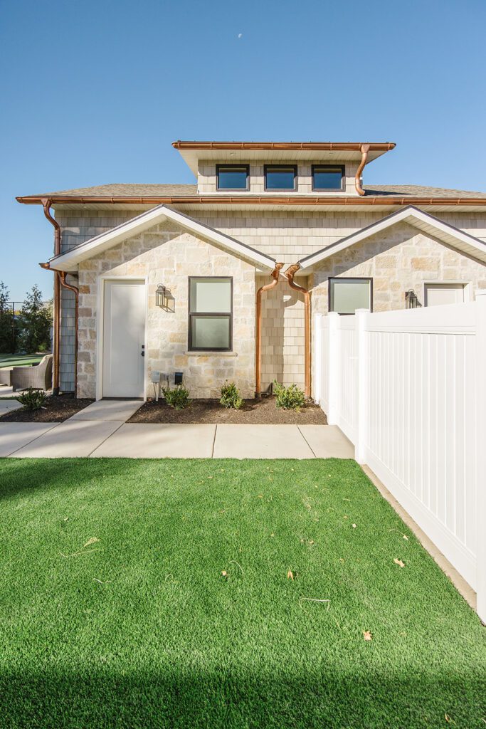 Back exterior of a Utah custom home with large windows, patio space, and beautiful yard design