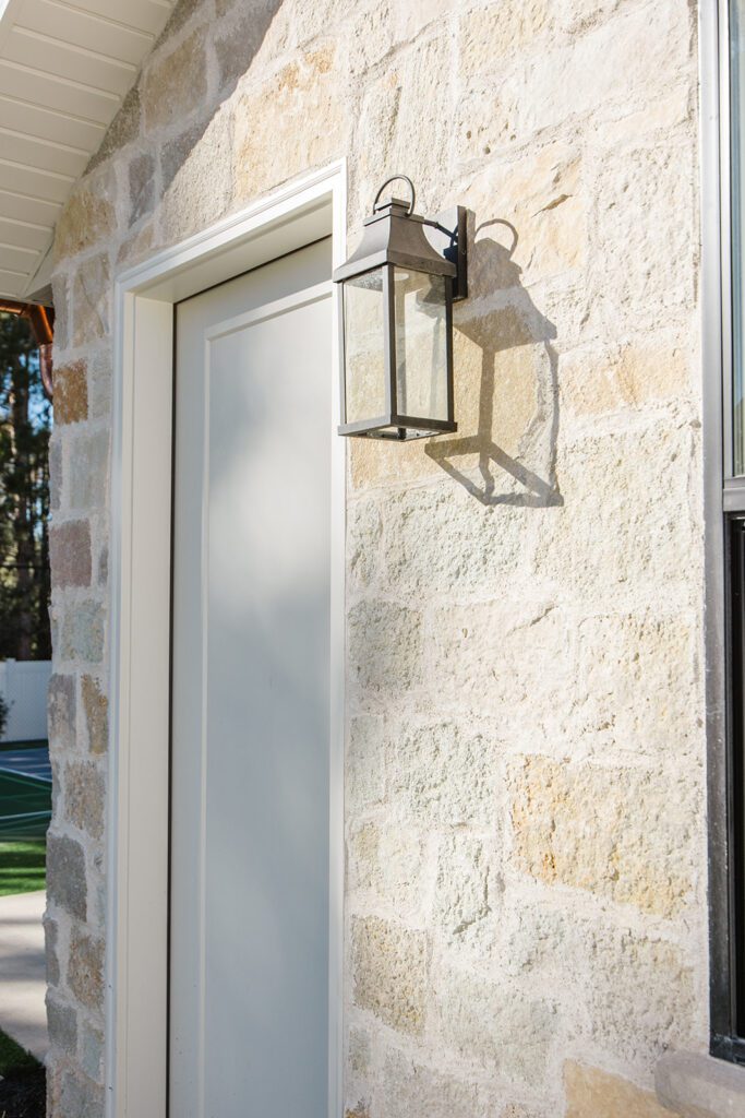 Back exterior of a Utah custom home with sport court, patio space, and beautiful yard design