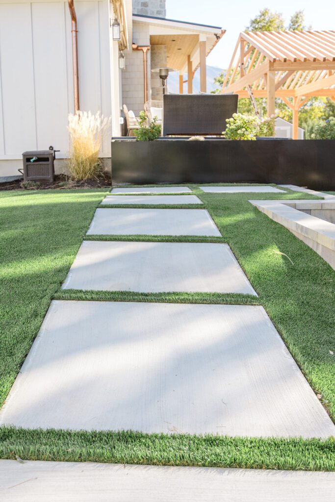 Back exterior of a Utah custom home with sport court, patio space, and beautiful yard design