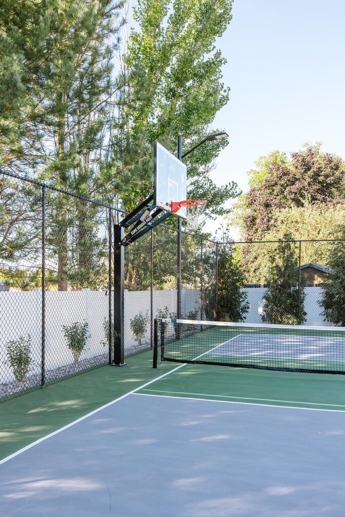Back exterior of a Utah custom home with large windows, patio space, and beautiful yard design