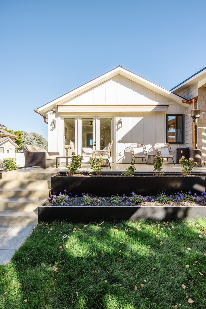Back exterior of a Utah custom home with large windows, patio space, and beautiful yard design
