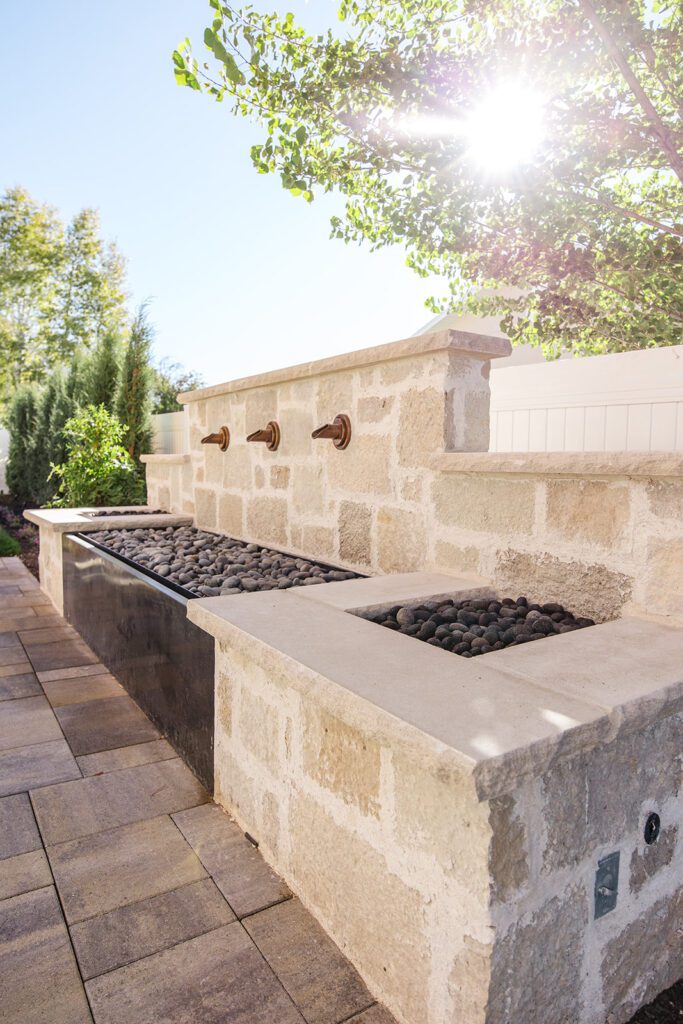 Back exterior of a Utah custom home with large windows, patio space, and beautiful yard design