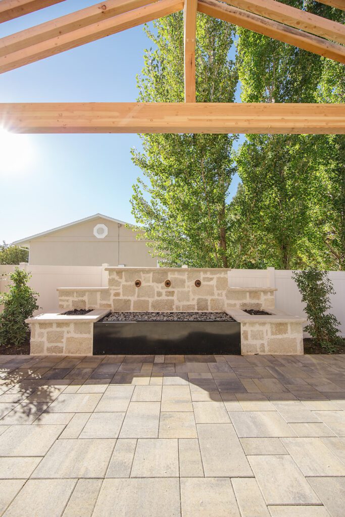Back exterior of a Utah custom home with large windows, patio space, and beautiful yard design