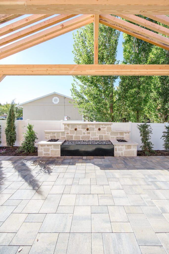 Back exterior of a Utah custom home with large windows, patio space, and beautiful yard design