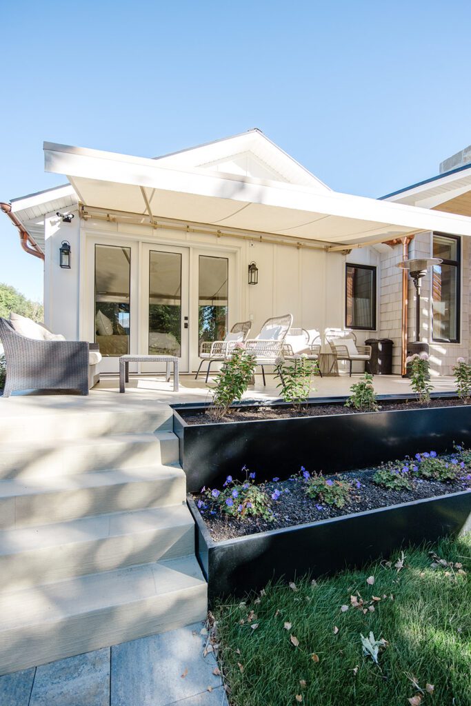 Back exterior of a Utah custom home with large windows, patio space, and beautiful yard design