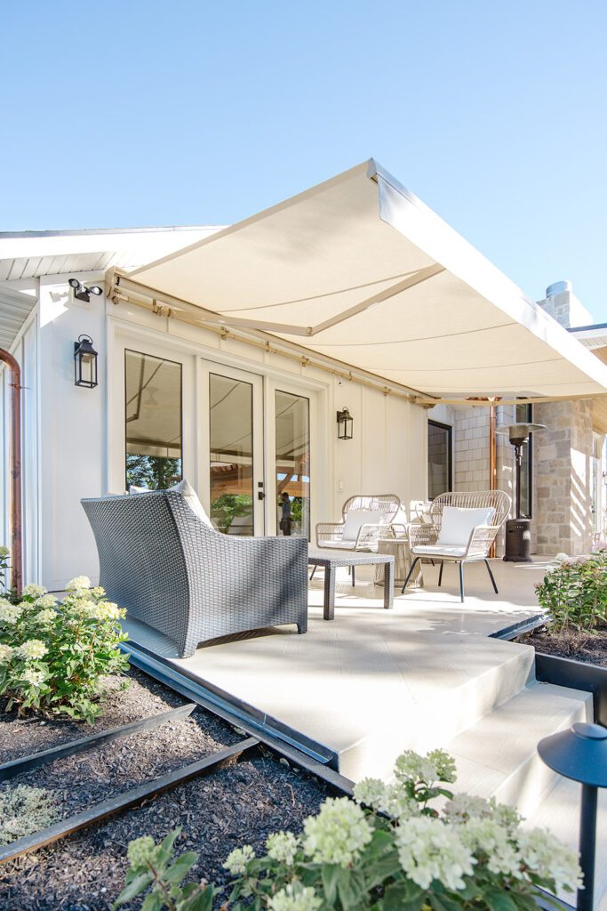 Back exterior of a Utah custom home with large windows, patio space, and beautiful yard design