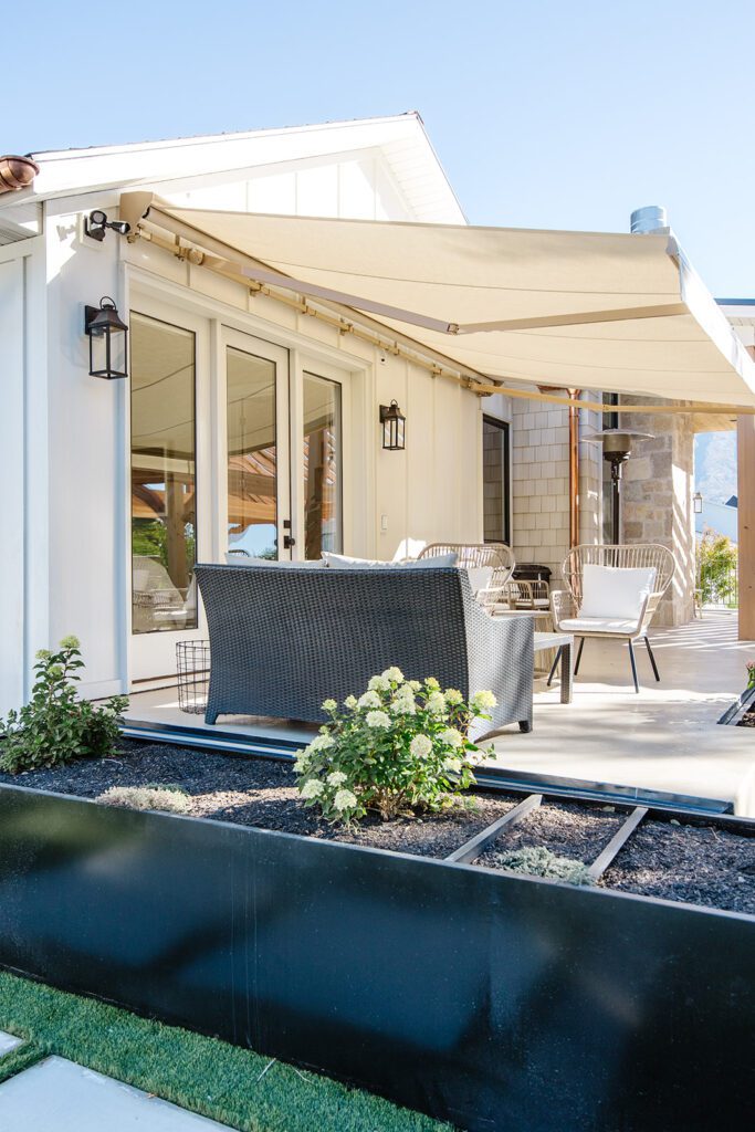 Back exterior of a Utah custom home with large windows, patio space, and beautiful yard design