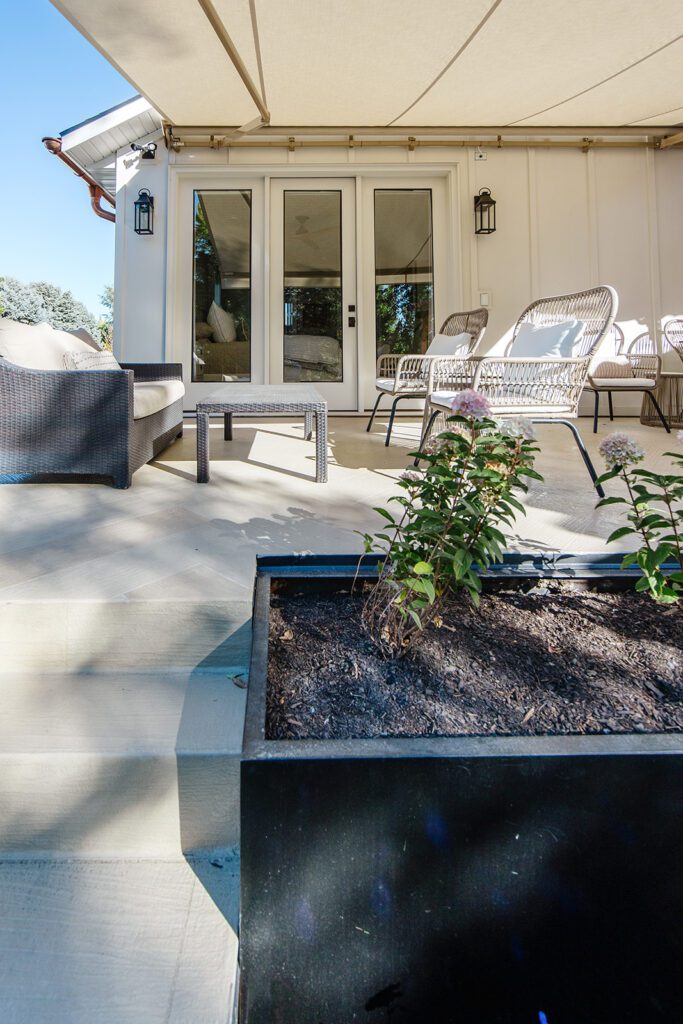 Back exterior of a Utah custom home with large windows, patio space, and beautiful yard design
