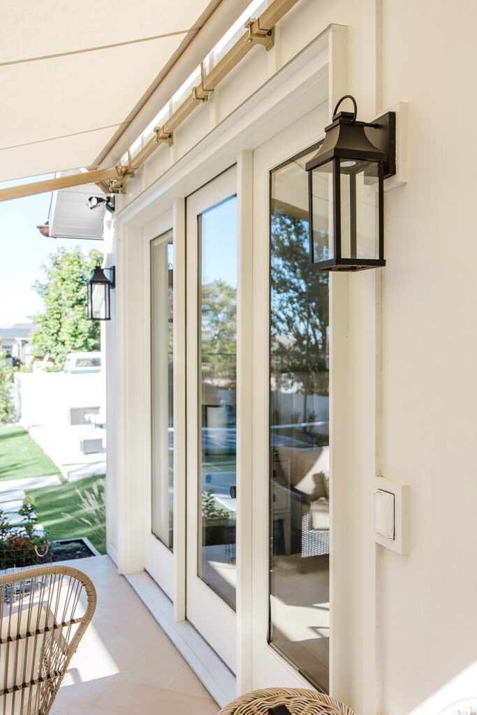 Back exterior of a Utah custom home with large windows, patio space, and beautiful yard design