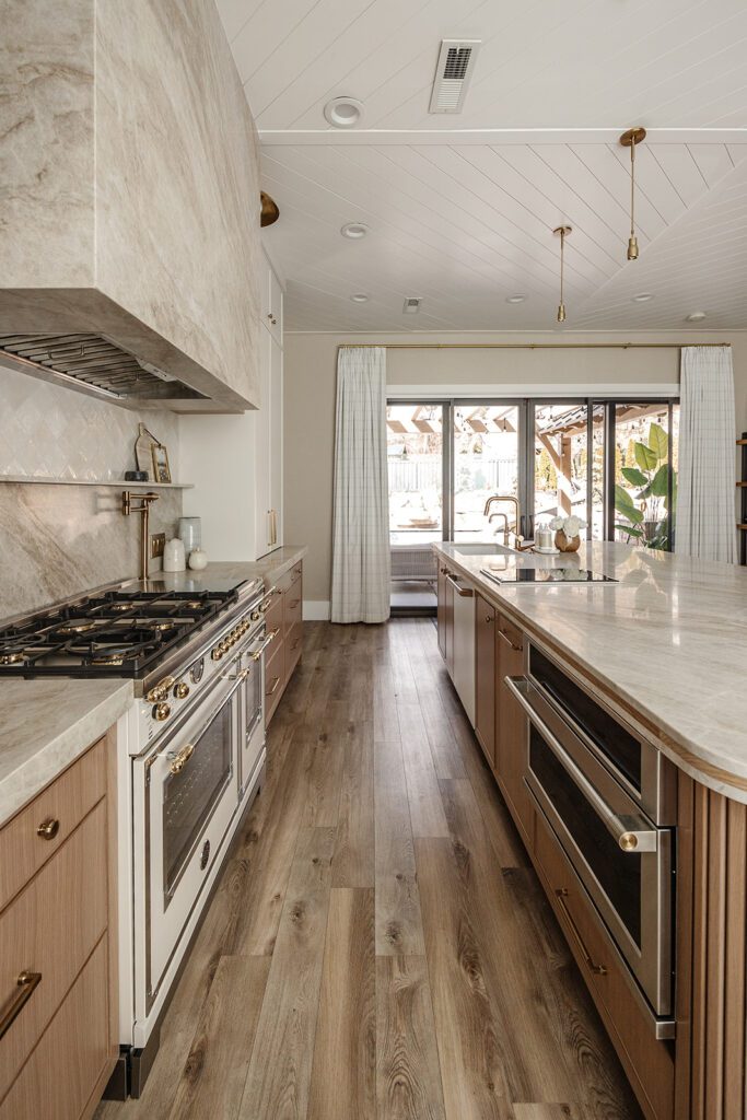 Wide-angle view of custom kitchen design with open shelving and brass accents in Alpine studio build