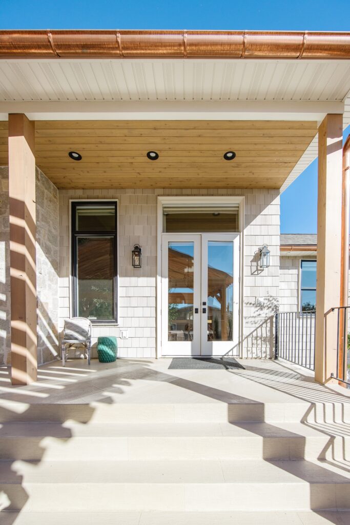 Back exterior of a Utah custom home with large windows, patio space, and beautiful yard design